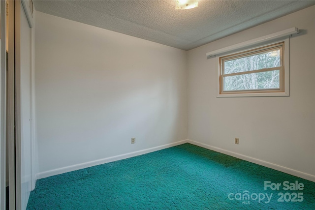 carpeted empty room featuring a textured ceiling