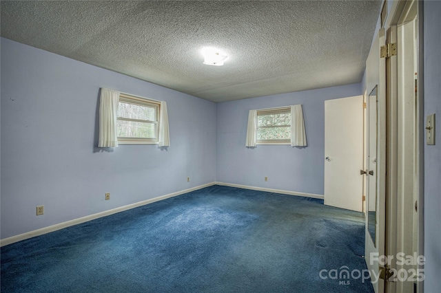 carpeted empty room featuring a textured ceiling and plenty of natural light