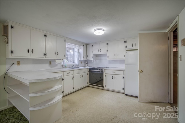 kitchen featuring white refrigerator, electric range oven, white cabinetry, and sink