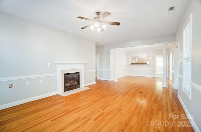 unfurnished living room featuring ceiling fan with notable chandelier and light hardwood / wood-style flooring