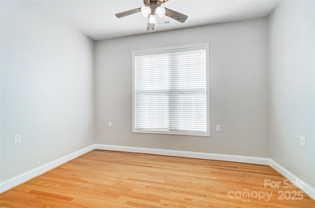 spare room with a wealth of natural light, ceiling fan, and wood-type flooring