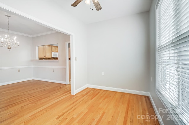 empty room featuring ceiling fan with notable chandelier, light hardwood / wood-style floors, and ornamental molding