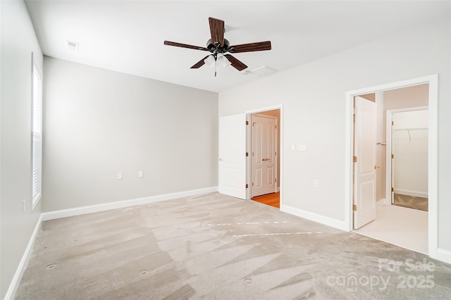 unfurnished bedroom with ceiling fan, a spacious closet, connected bathroom, light colored carpet, and a closet