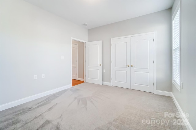 unfurnished bedroom featuring light colored carpet and a closet