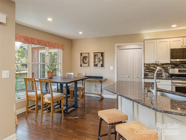 kitchen featuring backsplash, sink, dark stone countertops, white cabinetry, and stainless steel appliances