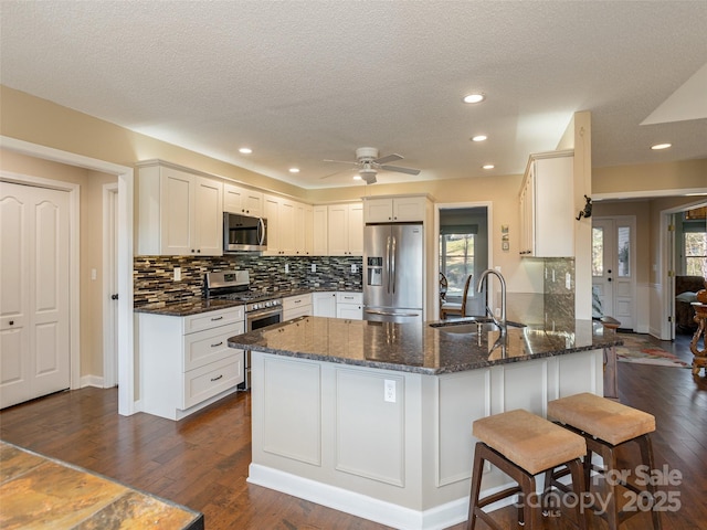 kitchen featuring sink, a kitchen breakfast bar, dark hardwood / wood-style floors, kitchen peninsula, and appliances with stainless steel finishes