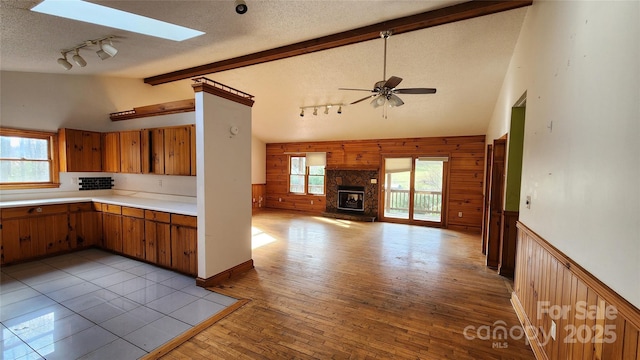 kitchen featuring ceiling fan, a healthy amount of sunlight, a stone fireplace, and wooden walls