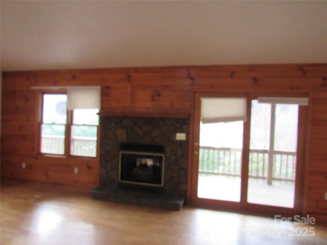 unfurnished living room featuring light hardwood / wood-style flooring and a stone fireplace