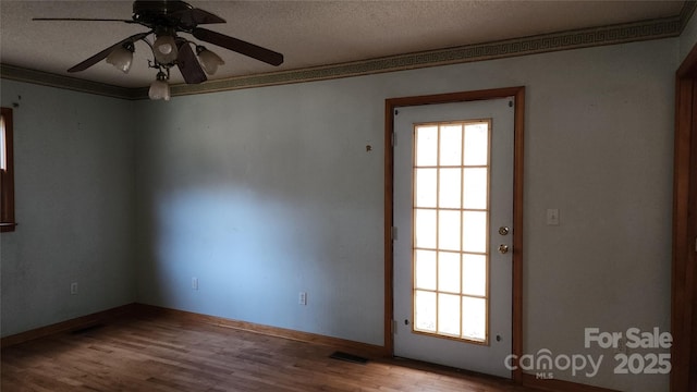 empty room with a textured ceiling, ceiling fan, crown molding, and hardwood / wood-style floors