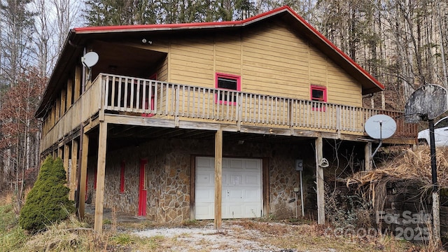 rear view of house featuring a garage and a wooden deck