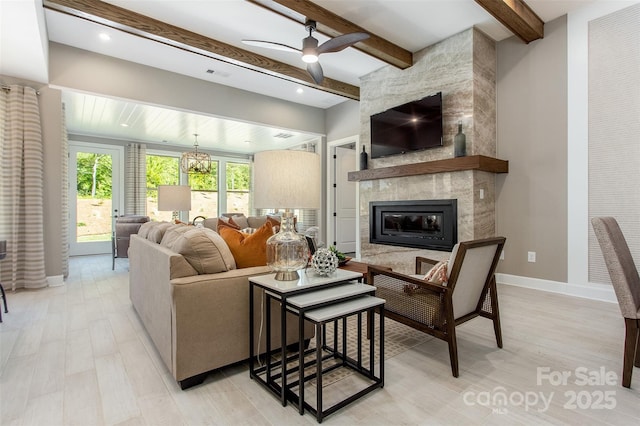 living room with a fireplace, beam ceiling, and ceiling fan with notable chandelier