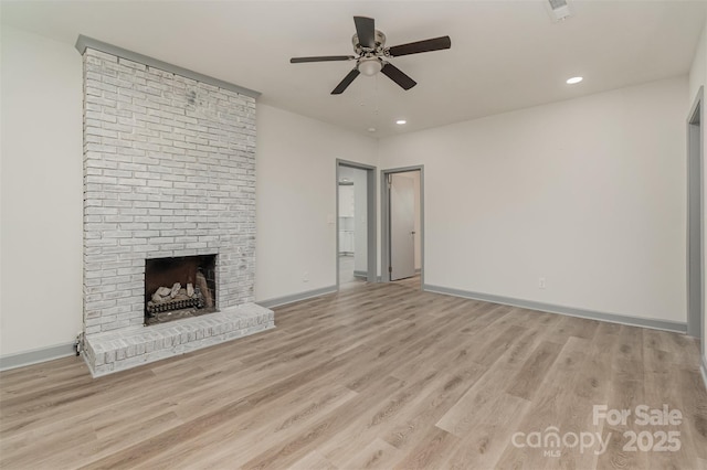 unfurnished living room with ceiling fan, a fireplace, and light wood-type flooring