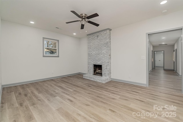 unfurnished living room featuring a fireplace, light hardwood / wood-style floors, and ceiling fan