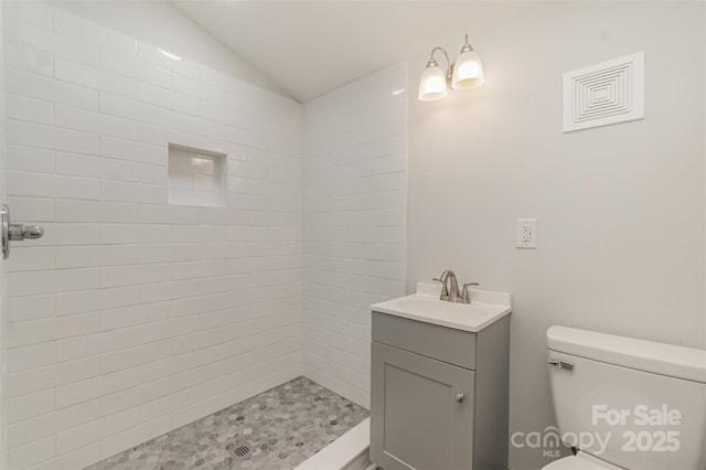 bathroom with a tile shower, vanity, and toilet