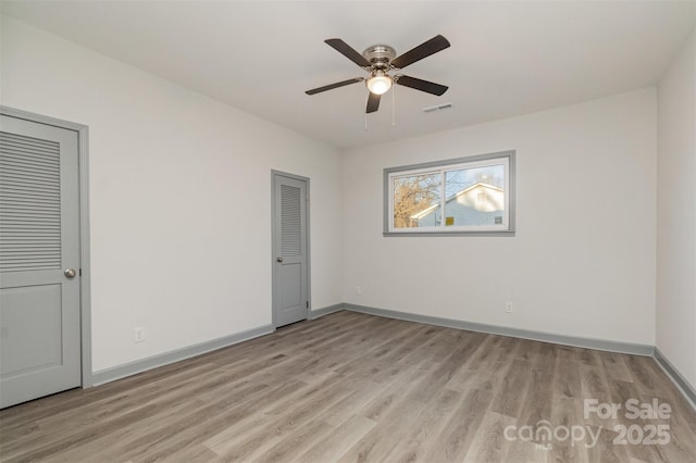 empty room with ceiling fan and light hardwood / wood-style floors