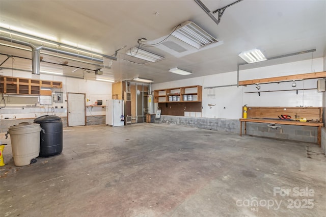 garage with a workshop area, white fridge, a garage door opener, and water heater