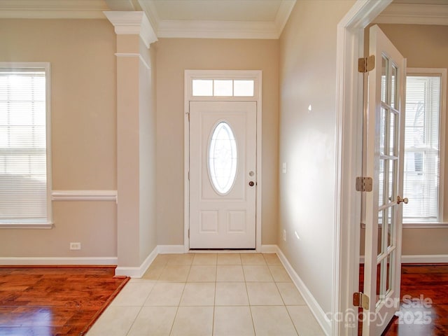 foyer entrance with crown molding and light tile patterned floors