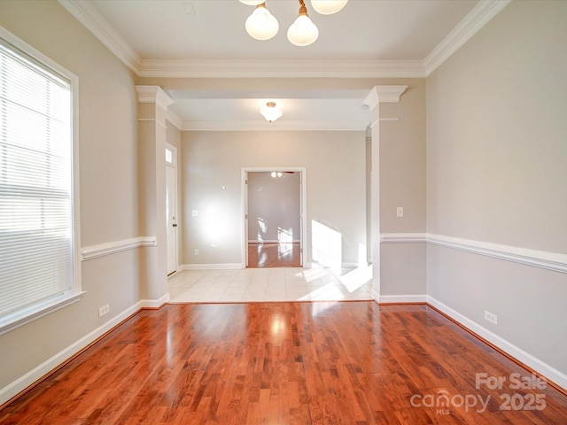 empty room featuring an inviting chandelier, light wood-type flooring, and ornamental molding