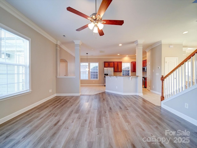 unfurnished living room featuring light hardwood / wood-style flooring, ornamental molding, and ornate columns