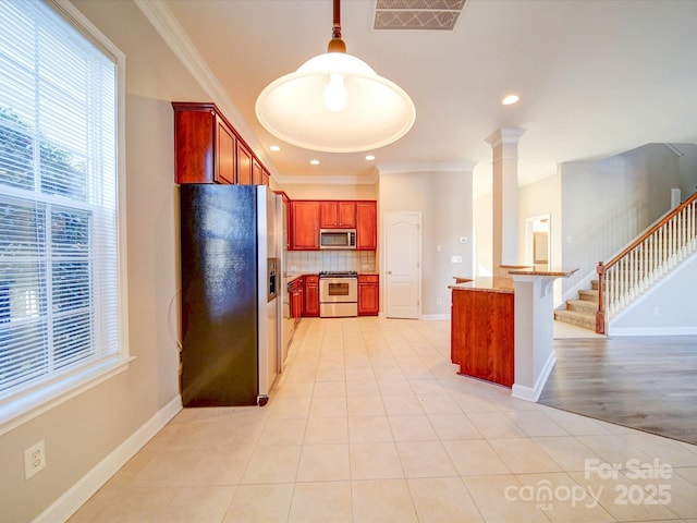 kitchen featuring appliances with stainless steel finishes, decorative light fixtures, backsplash, light tile patterned flooring, and ornamental molding