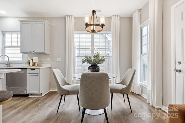 dining room featuring sink, light hardwood / wood-style flooring, and a notable chandelier