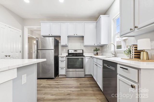 kitchen featuring stainless steel appliances, sink, white cabinets, and light hardwood / wood-style floors