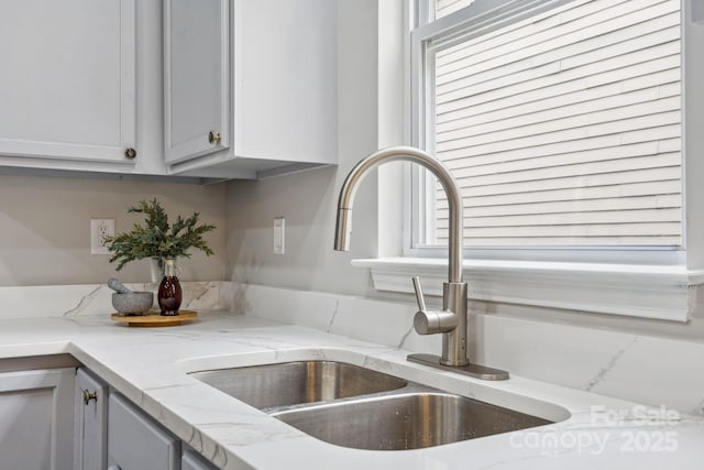 details with sink, gray cabinets, and light stone countertops