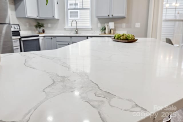 kitchen featuring light stone counters, sink, stainless steel range with electric cooktop, and gray cabinetry