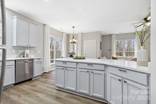 kitchen with ceiling fan with notable chandelier, dishwasher, gray cabinetry, hanging light fixtures, and light hardwood / wood-style flooring