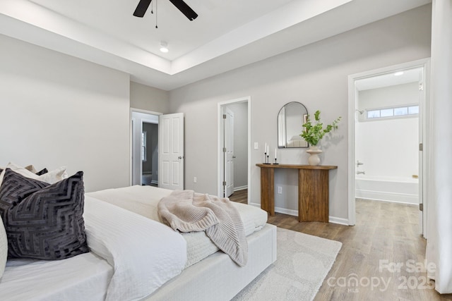 bedroom with ceiling fan, ensuite bath, and light hardwood / wood-style flooring