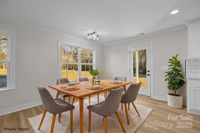 dining room with light wood-type flooring, ornamental molding, and an inviting chandelier