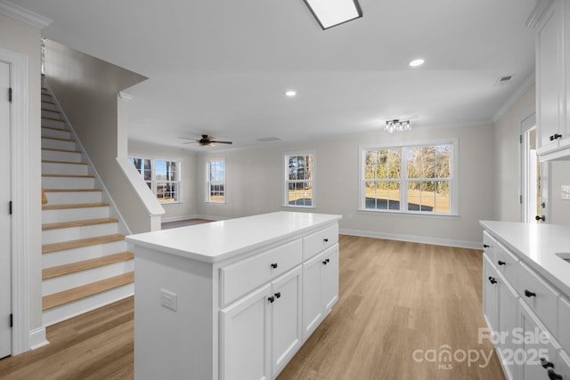 kitchen with a kitchen island, a healthy amount of sunlight, white cabinets, and light hardwood / wood-style floors