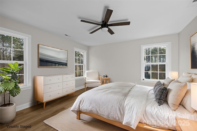 bedroom with dark hardwood / wood-style flooring, multiple windows, and ceiling fan