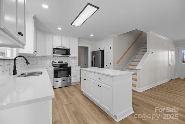 kitchen with stainless steel appliances, a kitchen island, sink, and white cabinets