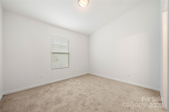 carpeted empty room with vaulted ceiling