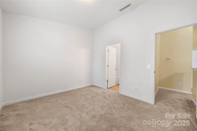 unfurnished bedroom with light colored carpet, a spacious closet, and connected bathroom