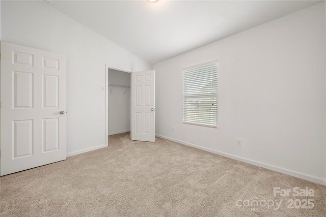 unfurnished bedroom with light carpet, a closet, and lofted ceiling