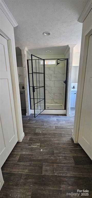 interior space featuring crown molding, hardwood / wood-style floors, a textured ceiling, and tiled shower