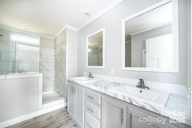 bathroom featuring a tile shower, vanity, wood-type flooring, and ornamental molding