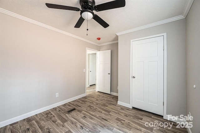 unfurnished bedroom with ceiling fan, wood-type flooring, and ornamental molding