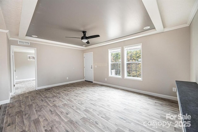 spare room with ceiling fan, light hardwood / wood-style floors, crown molding, and a tray ceiling