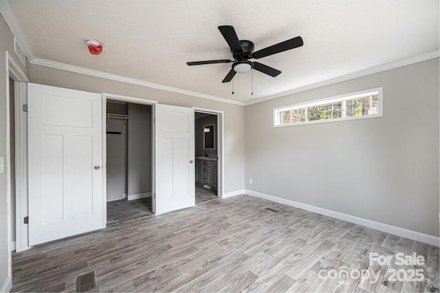 unfurnished bedroom with hardwood / wood-style flooring, ceiling fan, a textured ceiling, connected bathroom, and a closet