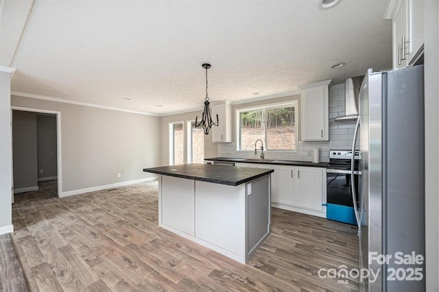 kitchen with white cabinetry, a center island, wall chimney exhaust hood, stainless steel appliances, and sink