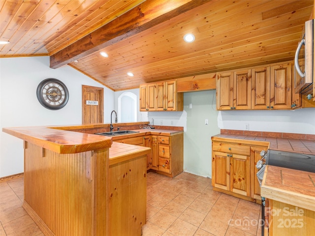 kitchen featuring stove, wooden ceiling, sink, vaulted ceiling with beams, and tile counters