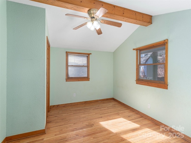 empty room with ceiling fan, a healthy amount of sunlight, lofted ceiling with beams, and light hardwood / wood-style flooring