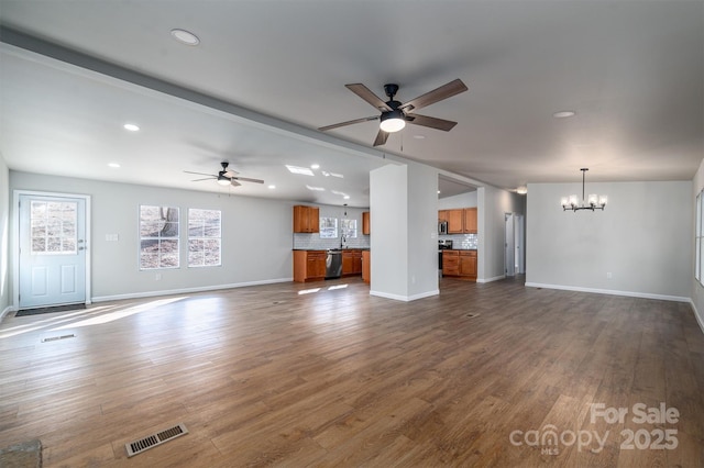 unfurnished living room featuring ceiling fan with notable chandelier, dark hardwood / wood-style flooring, and sink