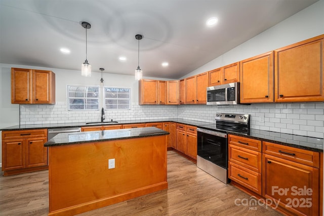 kitchen with pendant lighting, a center island, lofted ceiling, sink, and stainless steel appliances