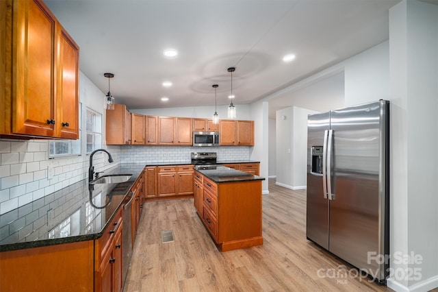 kitchen featuring a center island, sink, hanging light fixtures, stainless steel appliances, and light hardwood / wood-style floors