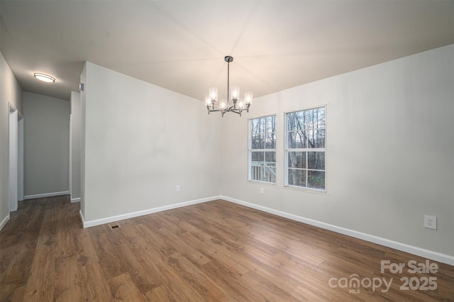 unfurnished room with hardwood / wood-style floors and a chandelier