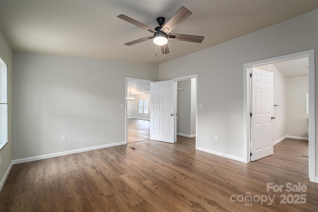 unfurnished bedroom with ceiling fan with notable chandelier and hardwood / wood-style flooring